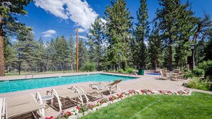 A swimming pool with lounge chairs and a grassy area with flowers. - Lovely, 3 Bdr, 2 Ba Walk To Eagle Chair, On Sierra Star Golf Course! (Mammoth Lakes)