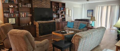 Una sala de estar acogedora con chimenea, una estantería, un sofá y una mesa de centro.