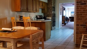 A kitchen with wooden cabinets, a dining table with chairs, and a ceiling fan. - 1-Level Patio Home Great Location 1 Block from Ocean - NO STEPS! w/ 1-car garage (North Myrtle Beach)