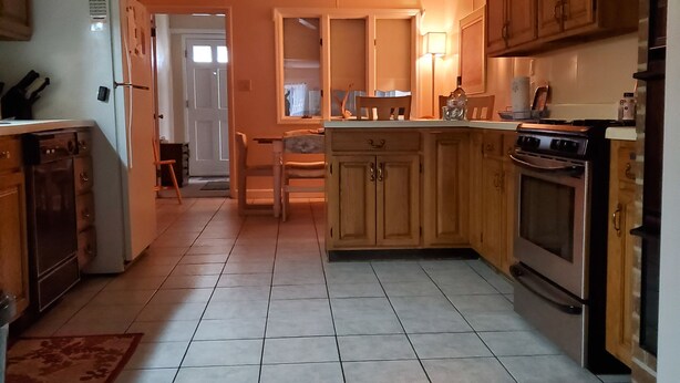 A kitchen with wooden cabinets, a refrigerator, a stove, and a ceiling fan. - 1-Level Patio Home Great Location 1 Block from Ocean - NO STEPS! w/ 1-car garage (North Myrtle Beach)