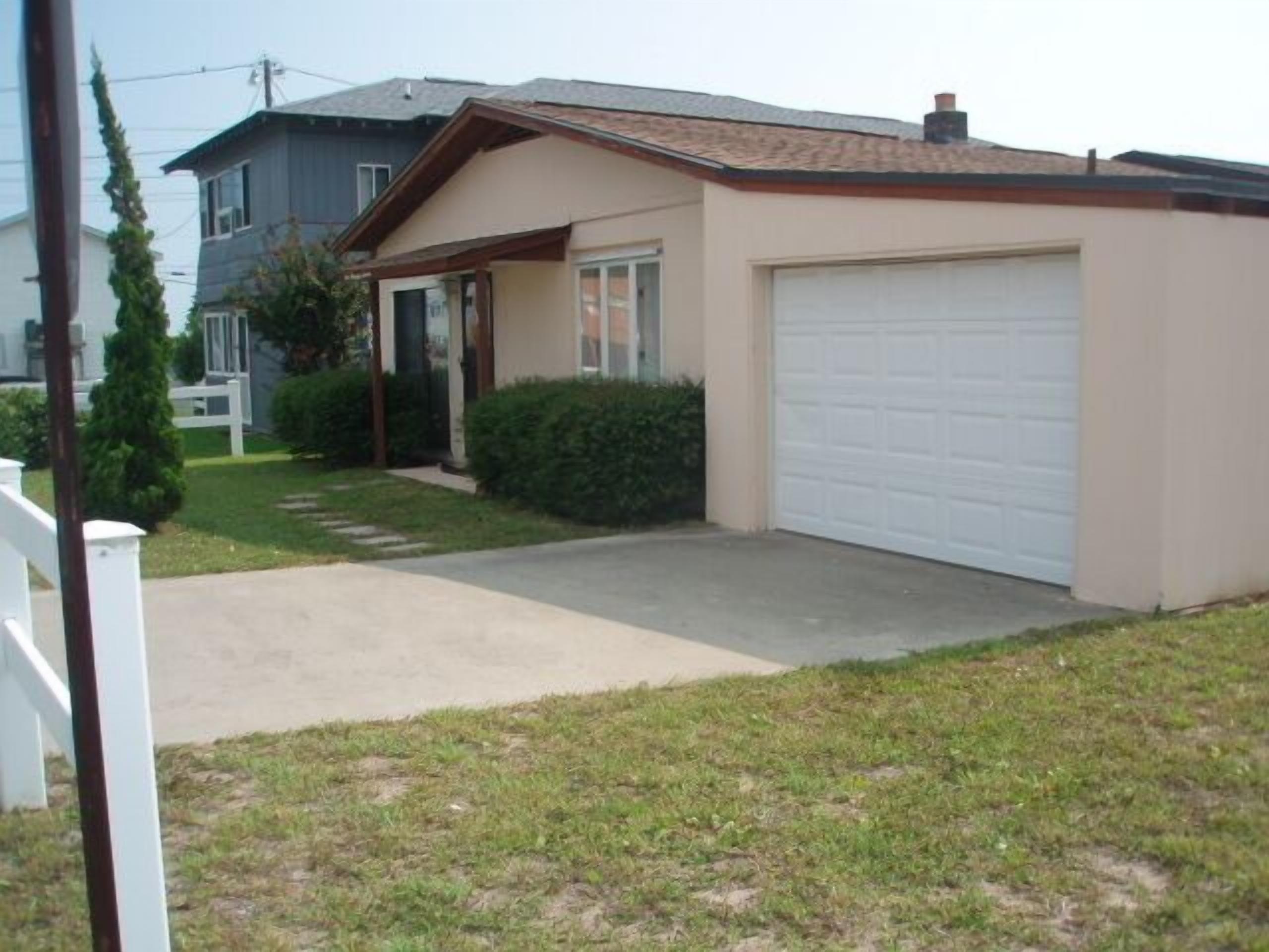 A single-story house with a garage, a front porch, and a small front yard.