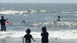 Eine Strandansicht mit spielenden Kindern am Wasser.