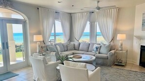 Un salon doté d’une grande fenêtre, d’un ventilateur de plafond et d’une cheminée.