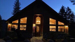 A lodge with a prominent entrance, large windows, and a stone facade. - Serenity Pines (Yosemite National Park)
