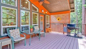 A covered outdoor deck with a ceiling fan, a grill, and a seating area with chairs and a table. - Serenity Pines (Yosemite National Park)