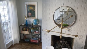 Una habitación con chimenea de ladrillo blanco, un globo en una estantería y un candelabro moderno.
