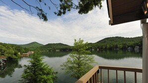 Une terrasse en bois surplombant un lac paisible, entouré de verdure et de collines.