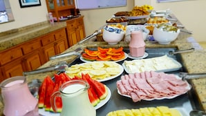 A buffet with various food items including fruits, cheeses, and meats. - Hotel Cathedral (Aparecida)