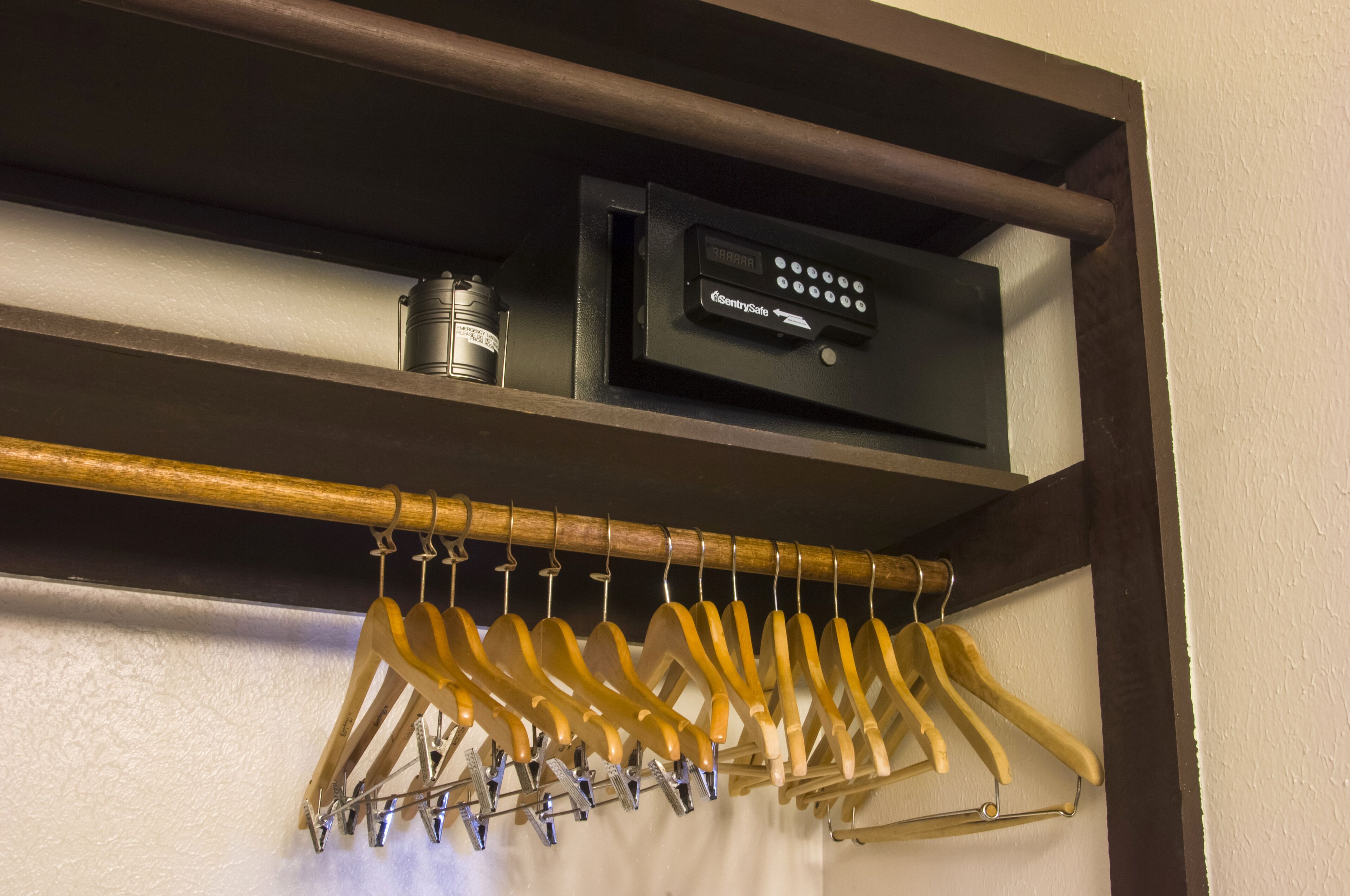 A shelf with a security device and a wooden hanger rack with hangers.