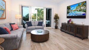 A living room with a sofa, armchair, coffee table, TV, and a potted plant. - 208 Mariners Club - Newly Renovated 3 bedroom, 3 Bath Townhome (Key Largo)