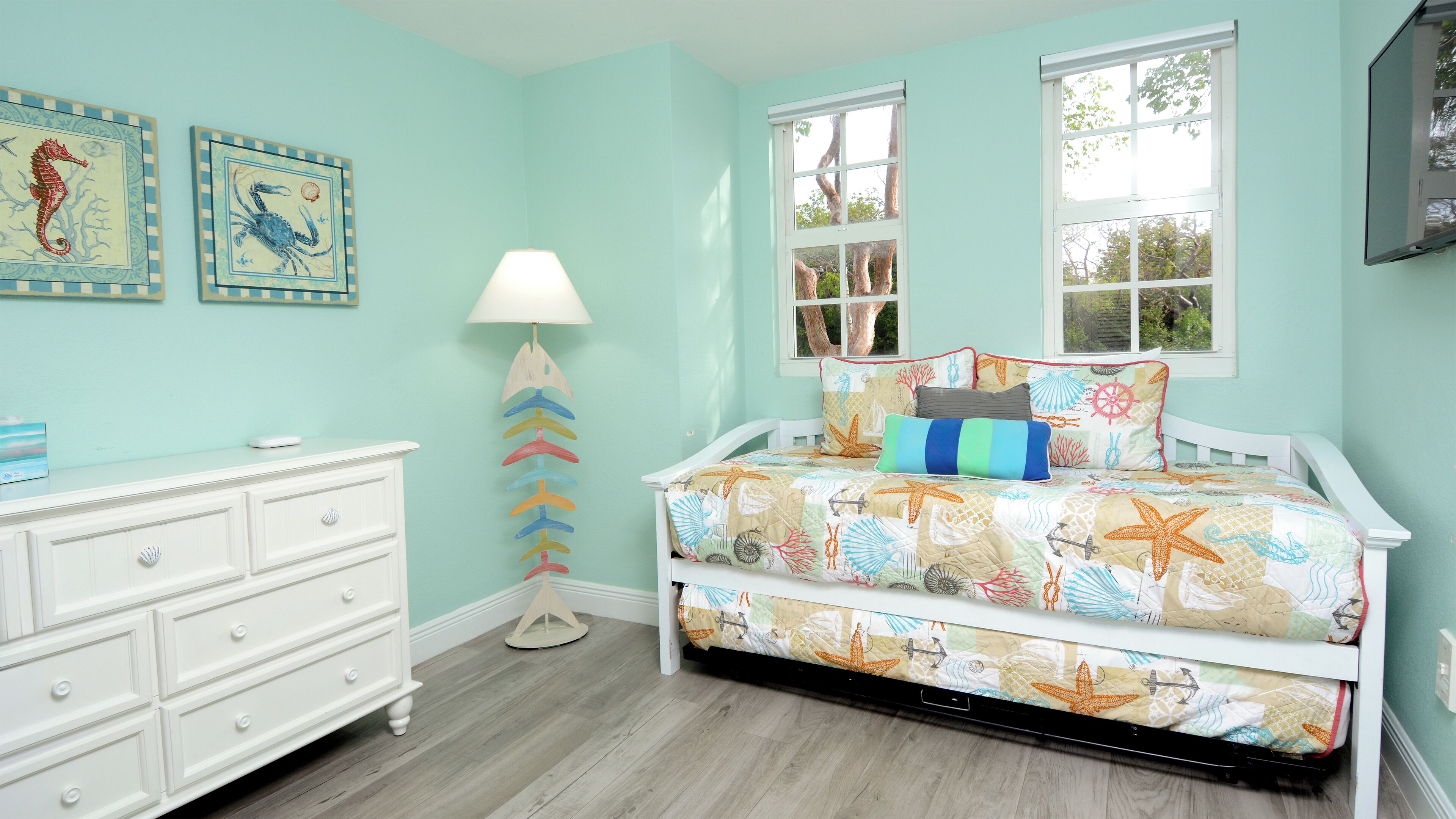 A bedroom with a bed, dresser, and two windows.