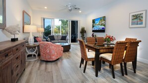 A modern living room with a dining area, large windows, and a ceiling fan. - 208 Mariners Club - Newly Renovated 3 bedroom, 3 Bath Townhome (Key Largo)