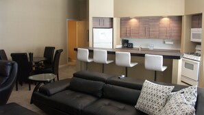 Ein modernes Wohnzimmer mit einer schwarzen Ledersofa und einem Essbereich mit einem kleinen Tisch und Stühlen.