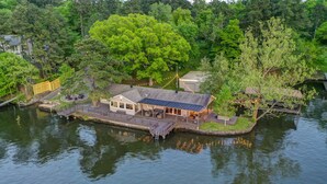 Una casa flotante con cubierta, paneles solares y un pequeño muelle.