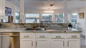 Una cocina amplia con una isla grande, armarios blancos y vistas a un lago.