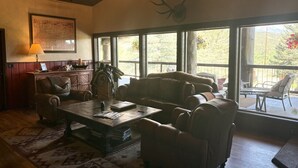 Una sala de estar acogedora con un ventanal grande, una chimenea y una cabeza de venado decorativa.