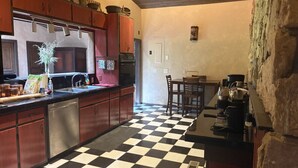 Una cocina con piso blanco y negro a cuadros, armarios de madera y pared de piedra.