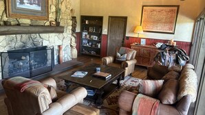 Una sala de estar acogedora con sofás de cuero, una chimenea de piedra, una estantería y un mapa en la pared.