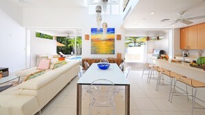 Cocina moderna con comedor, que incluye una mesa larga, sillas transparentes y una isla central con un cuenco azul.