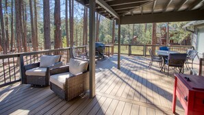 Een overdekt terras met rieten meubels, een barbecue en een rode kast.