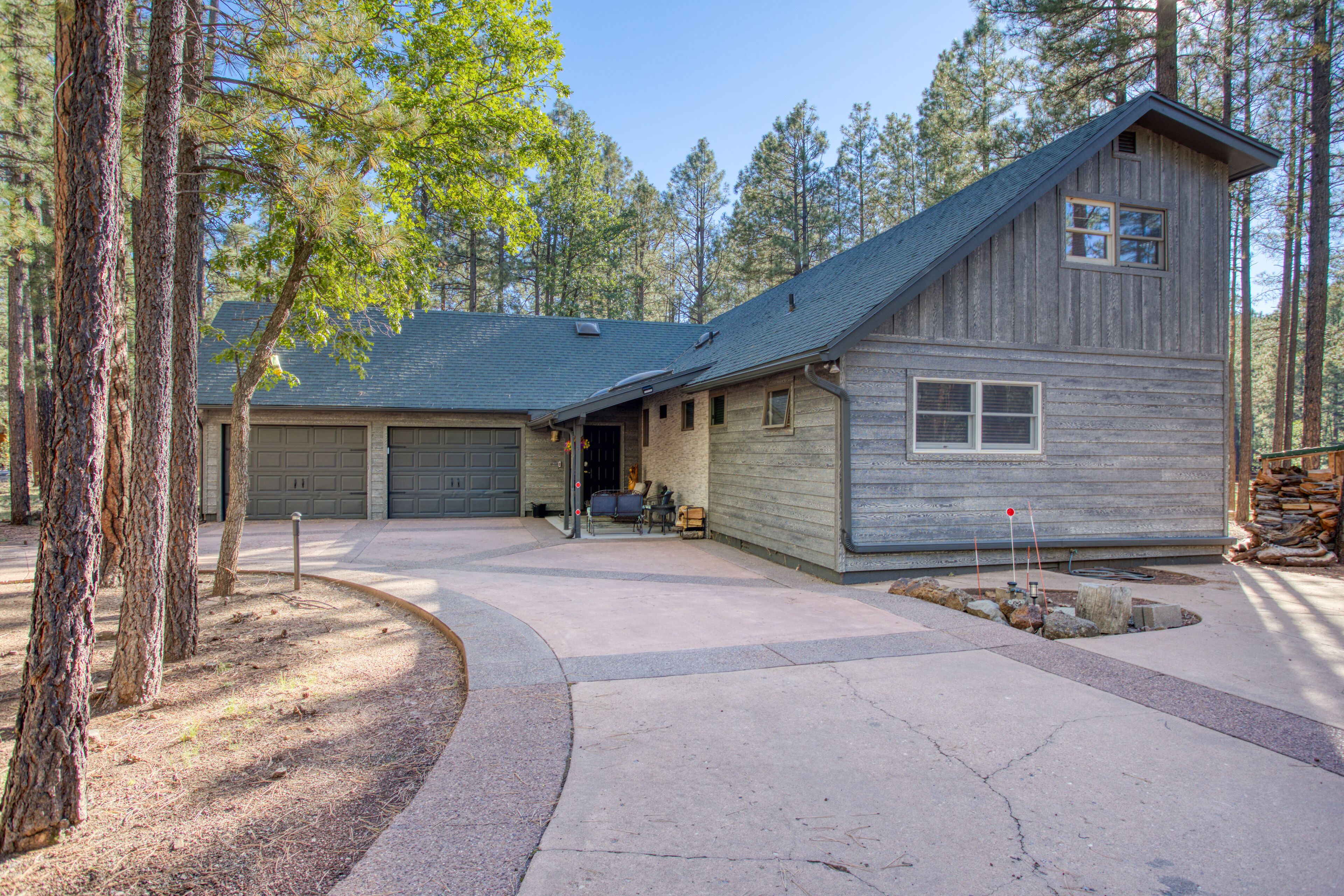 A two-story house with a garage, driveway, and a landscaped area with trees.