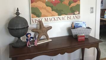A wooden console table with a framed poster of Michigan, a globe, a starfish, and a small figurine.