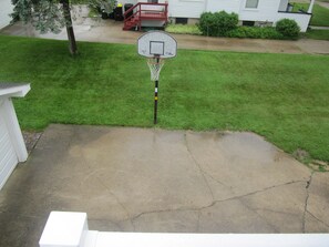 A residential basketball hoop in a front yard with a concrete driveway leading to a white garage.