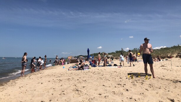 Une plage bondée où les gens se prélassent au soleil et se baignent.