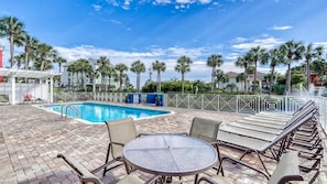 Área de piscina no terraço com espreguiçadeiras, uma mesa e piscina.