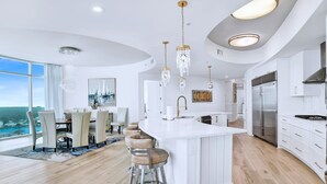 A modern kitchen with a large island, stainless steel appliances, and pendant lighting.