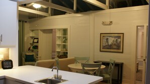 Una cocina compacta con un lavamanos, una zona de comedor con mesa y sillas, y una pequeña isla.