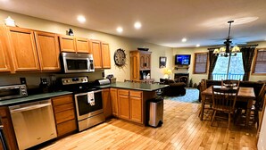 A spacious kitchen with wooden cabinets, a stainless steel stove, and a large island. - Lake Placid Pinehill Townhome, Your "Next Adventure" vacation (Lake Placid)