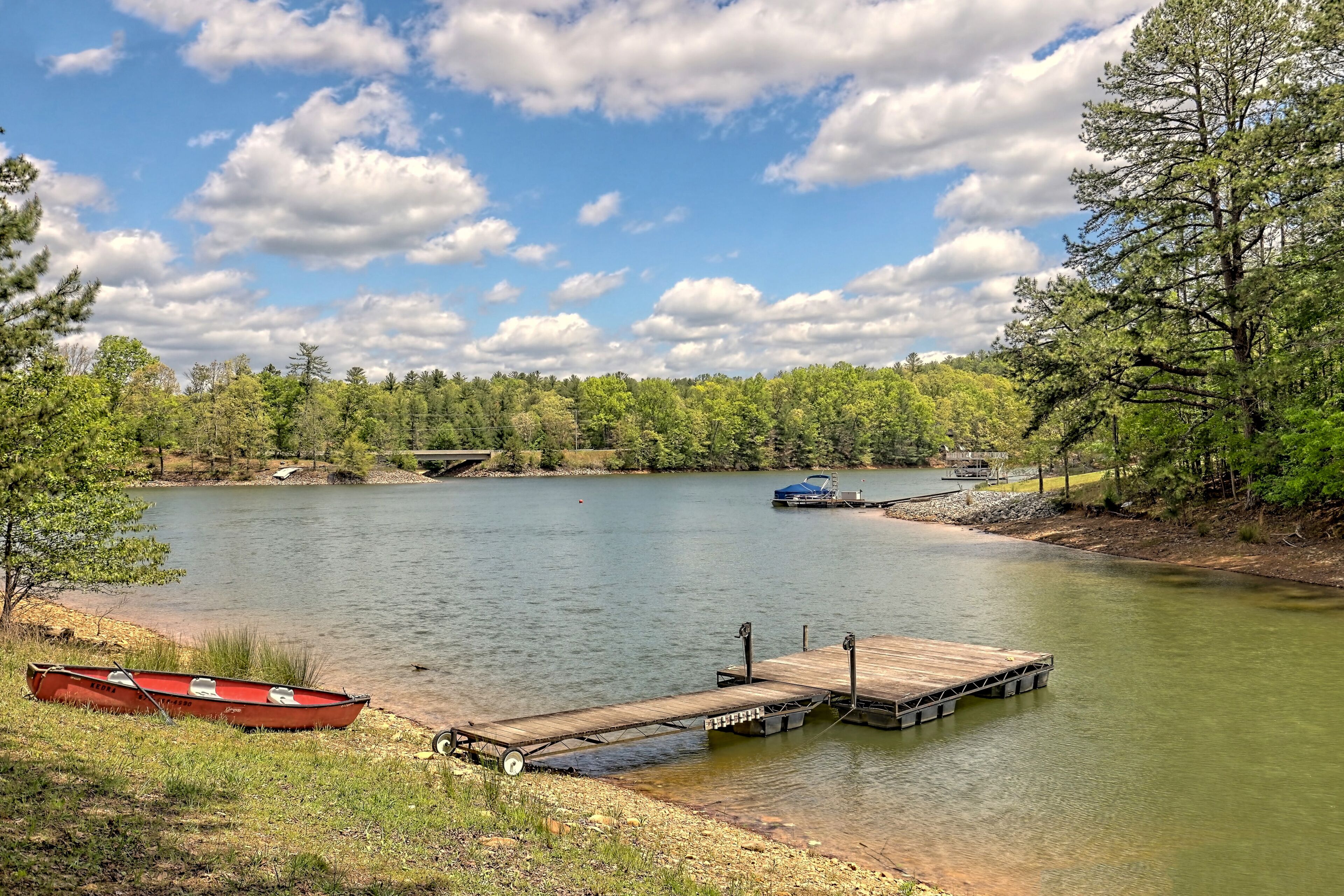 Un lac paisible avec un quai et un bateau rouge.