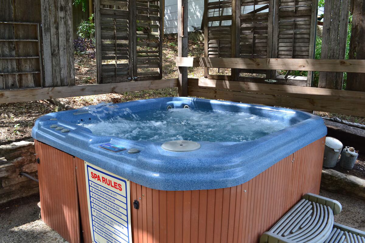 A spa hot tub with a sign listing spa rules, surrounded by wooden fencing and a wooden deck.