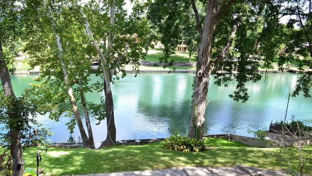 Um ambiente tranquilo à beira do lago, com gramado, um píer e área de estar com cadeiras e mesa.