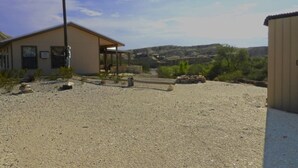 Een gebouw met een grindpad, een overdekte patio en uitzicht op een glooiend landschap.