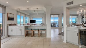 Una cocina amplia con una isla grande, taburetes de bar y vista al océano.