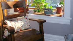 Ein Zimmer mit einem Holzstuhl und einem Fenster mit Blick auf eine Wohngegend.