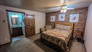 A bedroom with a wooden bed, a ceiling fan, a brick wall, and framed pictures. - Downtown Montrose, Colorado (Montrose)