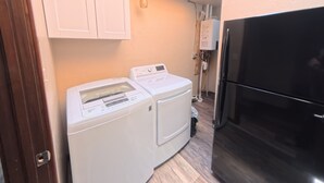 Een kleine keuken met een wasmachine, een koelkast en houten kastjes.
