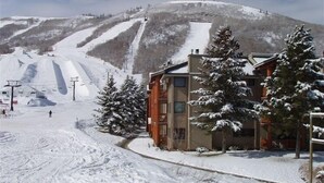 Une station de ski enneigée, avec un bâtiment doté de nombreuses fenêtres et d’un toit en pente.