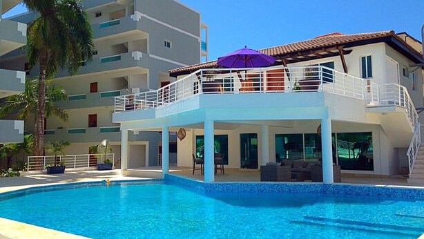 A modern hotel with a pool, balconies, and outdoor seating.