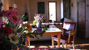 A dining area with a wooden table and chairs, a vase with flowers, and a painting on the wall. - Best Sunsets in town! (Marfa)