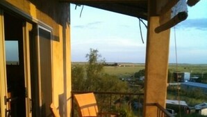 A balcony with wicker furniture, a small table, and a pair of shoes on the floor. - Best Sunsets in town! (Marfa)