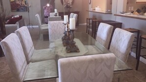 A dining area with a glass-top table surrounded by cushioned chairs, a chandelier, and a decorative centerpiece. - BEAUTIFUL SUNRISES.  THREE MASTER SUITES (Palm Desert)