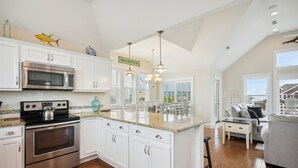 A spacious kitchen with white cabinetry, stainless steel appliances, and a large island. - 5543-C-Dreams - Nags Head Ocean View Home | Private Pool (Nags Head)