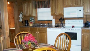 A wooden cabin-style kitchen with a dining table, chairs, and a microwave.