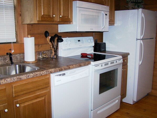Una cocina equipada con microondas, estufa y refrigerador.