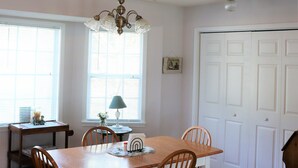 A dining area with a wooden table, four chairs, a chandelier, and a patterned rug. - Lakefront Cottage on Lake Marion (Summerton)
