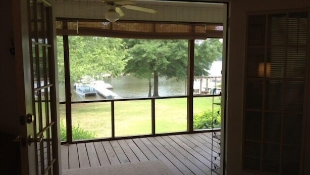A view from a room with a large window overlooking a river, a boat, and a tree. - Lakefront Cottage on Lake Marion (Summerton)